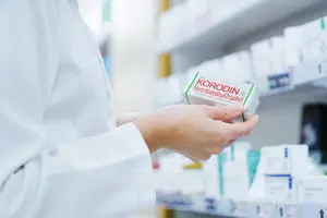 Apotheker nimmt Korodin Herz-Kreislauf Tropfen aus dem Regal